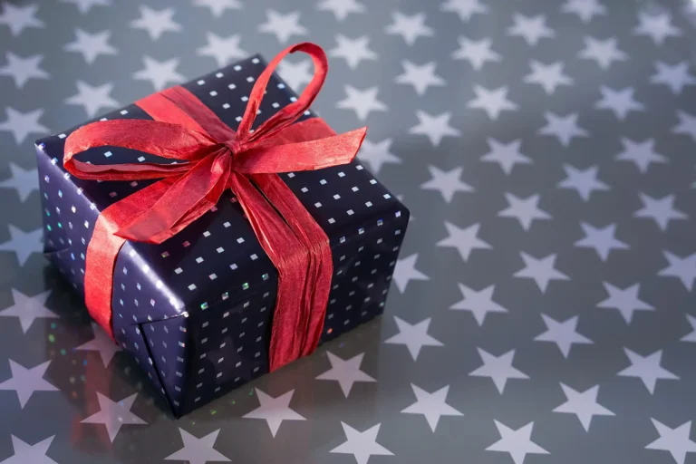 Immagine di un pacco regalo con grande fiocco rosso e carta a pois